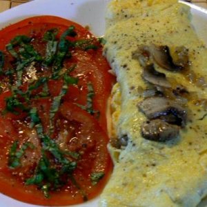 Onion, mushroom and cheese omelette and a side of vine tomato with basil chiffonade, sea salt, ground peppercorns and a drizzle of olive oil.
