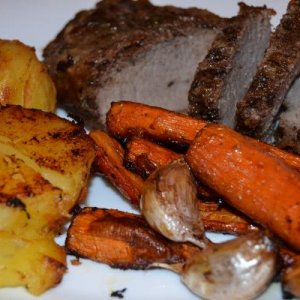 Herb crusted beef with roast potatoes and roasted garlic and carrott