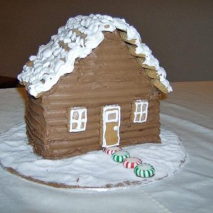 Gingerbread house CAKE.  The cake is gingerbread and decorated with gingerbread cookies for roof tiles, doors and windows.  It is frosted with chocola