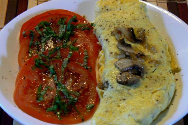 Onion, mushroom and cheese omelette and a side of vine tomato with basil chiffonade, sea salt, ground peppercorns and a drizzle of olive oil.