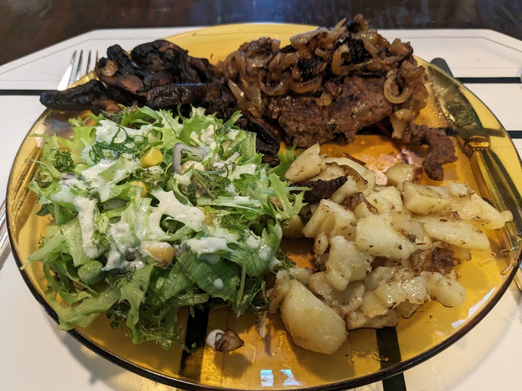 Hamburger steak with soft onions, mushrooms, home fries, and a salad with blue cheese dressing.jpg